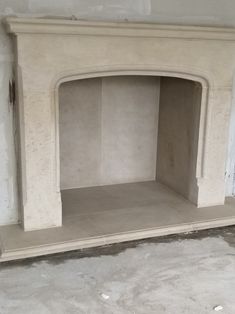 an empty fireplace in a room with no one around it and the wall is bare