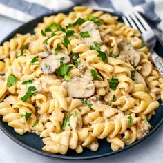 a blue plate topped with pasta covered in mushroom sauce and garnished with parsley