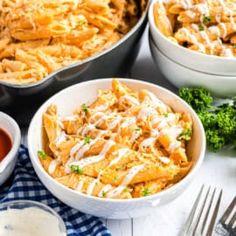 several bowls filled with pasta and sauce on top of a white tablecloth next to silverware