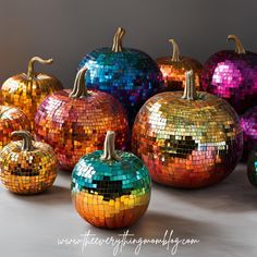 many colorful pumpkins are arranged in a row on the table, with one painted like a disco ball