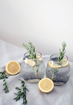 two clear vases filled with lemon slices and rosemary sprigs