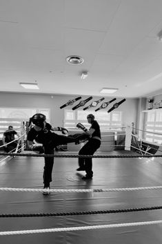 two people in a boxing ring with ropes on the ground and one person holding a punching glove