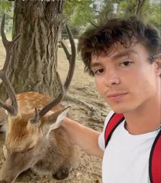 a young man standing next to a deer