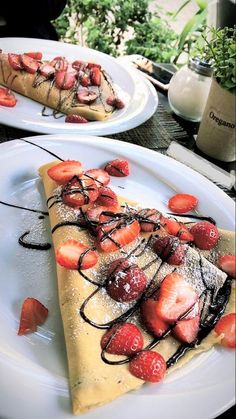 two white plates topped with desserts covered in strawberries