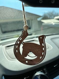 a wooden horse shoe ornament hanging from the dashboard of a car