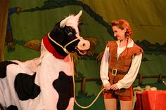 a woman standing next to a cow on top of a stage