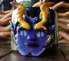 a close up of a cup on a table with a purple face and horns painted on it