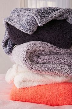 several towels stacked on top of each other in different colors and sizes, with one folded over the edge