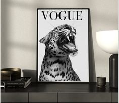 a black and white photo of a leopard with its mouth open on a table next to a lamp