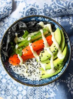 a bowl filled with vegetables and dressing on top of a blue table cloth