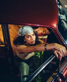 a woman leaning out the window of a car with her hand on the door handle