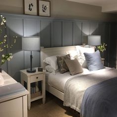 a white bed sitting in a bedroom next to a night stand with two lamps on top of it