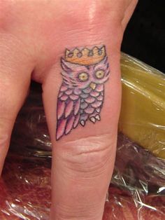 an owl with a crown tattoo on its finger