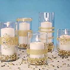 a group of white candles sitting on top of a table next to each other with gold glitter around them