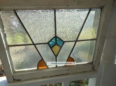 an old stained glass window on the outside of a house with white trim and wood frame