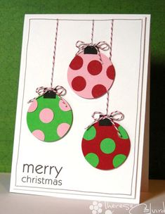 two christmas ornaments hanging from strings on a card