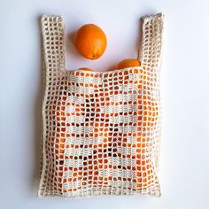 an orange sitting on top of a crocheted bag