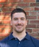 a man standing in front of a brick wall