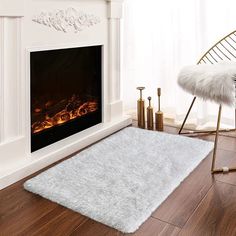 a living room with a fireplace, chair and rug in front of the fire place