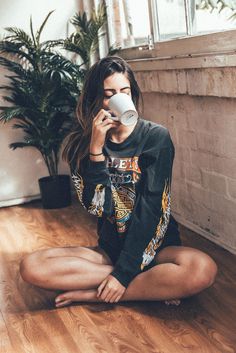 a woman sitting on the floor drinking from a cup