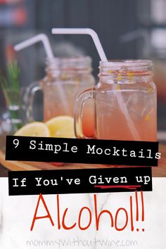 two mason jars filled with drinks sitting on top of a wooden table next to lemons