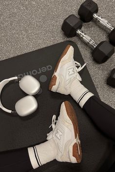 a pair of sneakers and headphones are sitting on a mat next to dumbbells