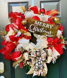 a christmas wreath on the front door with red and white bows, leopard print ribbon and merry lettering