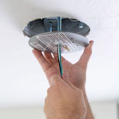 a person is holding an electrical wire in their hand and plugged into the ceiling