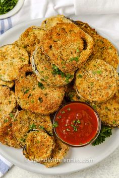 a white plate topped with crab cakes next to a bowl of ketchup and parsley