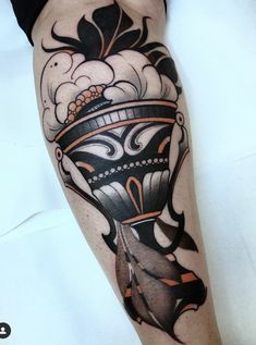 a man's leg with a tattoo on it that has an image of a hat and feathers