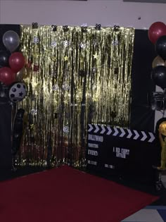 a red carpet with balloons and streamers in front of a gold curtain on the wall