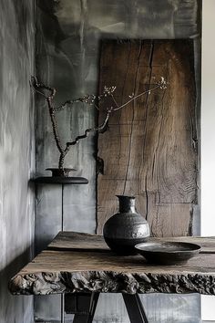 a wooden table topped with two vases next to a metal wall mounted art piece