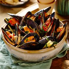 a bowl filled with mussels on top of a table