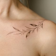 a woman with a tattoo on her chest has a leaf design on it's left shoulder