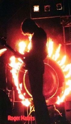 a man standing on top of a stage with fire in the background