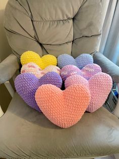 several heart shaped pillows sitting on top of a chair