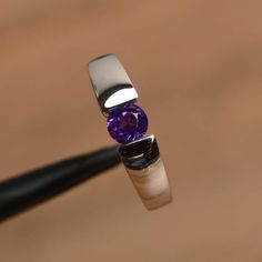 It is a natural amethyst ring. The main stone is 5 mm*5 mm round cut.weight about 0.48 carats.The basic metal is sterling silver and plated with rhodium.To change the metal to a solid gold (white/rose) or platinum is also available, please ask for a quotation if you want.You can also go to my shop Home for more elegant rings: https://www.etsy.com/shop/godjewelry?ref=hdr_shop_menu Amethyst is February birthstoneMore amethyst rings:https://www.etsy.com/shop/godjewelry?ref=seller-platform-mcnav&sec Minimalist Amethyst Birthstone Ring For Anniversary, Minimalist Amethyst Birthstone Promise Ring, Modern Round Birthstone Ring With Tension Setting, Purple Solitaire Birthstone Ring, Round Cut White Gold Amethyst Birthstone Ring, Minimalist Silver Amethyst Ring, Silver Amethyst Birthstone Ring, White Gold Amethyst Birthstone Ring With Round Cut, Amethyst Birthstone Ring In White Gold