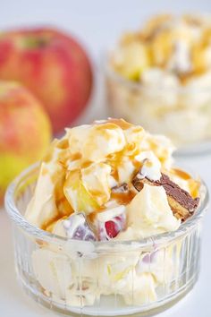 two bowls filled with dessert sitting on top of a white table next to an apple