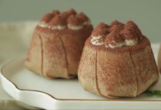 three small desserts on a white plate with green garnish around the edges