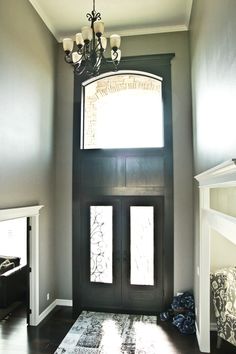 an entryway with a black door and chandelier