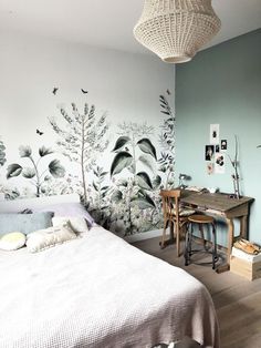 a bedroom with a bed, desk and wall mural