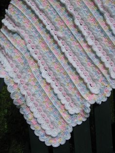 a crocheted blanket sitting on top of a wooden fence