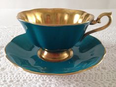 a tea cup and saucer sitting on top of a white tablecloth covered table