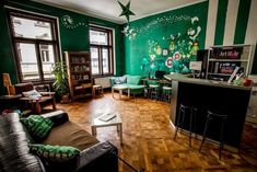 a living room filled with furniture next to a kitchen and dining room table in front of a green painted wall