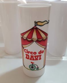 a white coffee cup with a red and yellow umbrella on it's side next to two cups that say cinco de mayo