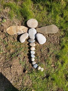 a dragon made out of rocks sitting on top of a grass covered field next to stones