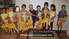 a group of children holding up giraffes made out of construction paper in front of a door