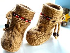 a pair of knitted boots sitting on top of a white table next to a stuffed animal