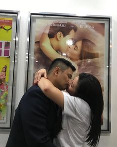 a man and woman kissing in front of a movie poster