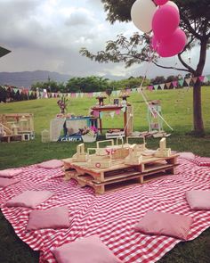 a picnic table with pink and white balloons on it in the middle of a field